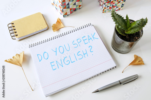Do you speak english written in a notebook on white table