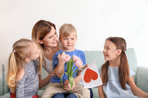 Mother receiving gifts from her cute little children at home