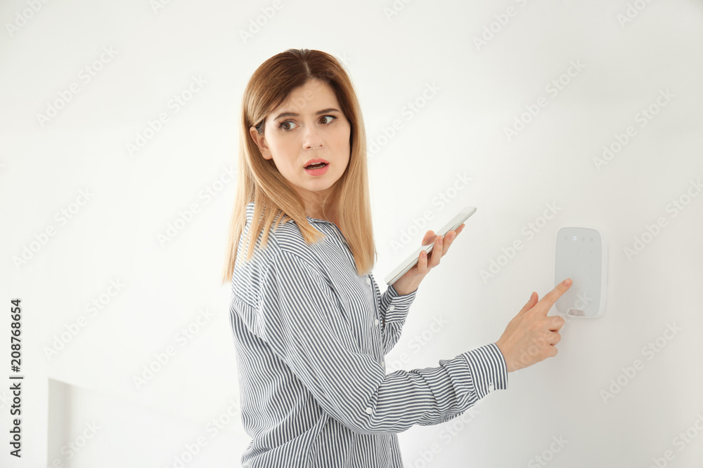 Frightened woman with tablet using security system indoors Frightened woman with tablet using security system indoors