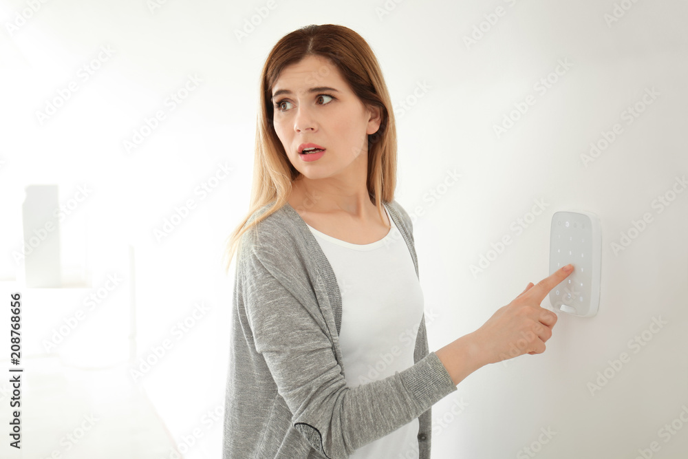 Frightened woman using security system indoors Frightened woman using security system indoors