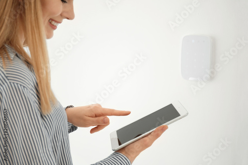Woman with tablet near security system indoors