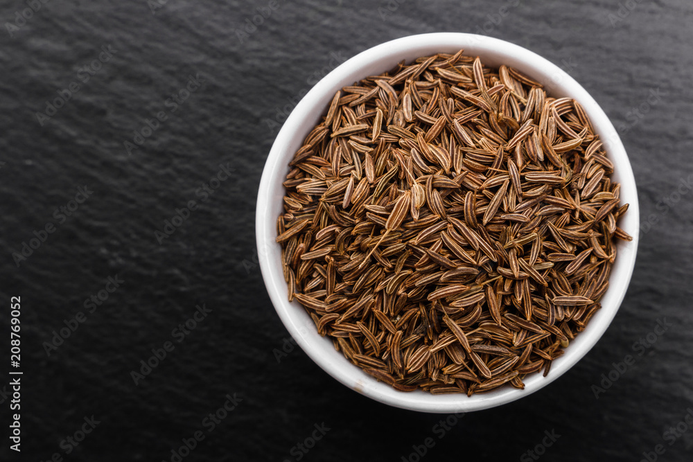 Seeds of cumin on a dark stone background Seeds of cumin on a dark stone background