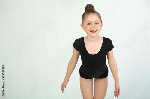 beautiful young girl engaged in gymnastics on a white background in a black suit