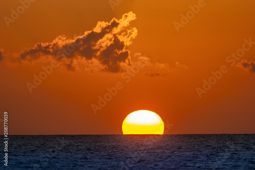 Fototapeta Naklejka Na Ścianę i Meble -  sun diving into the sea as big red boule, sailing yacht sailing straight into the sun