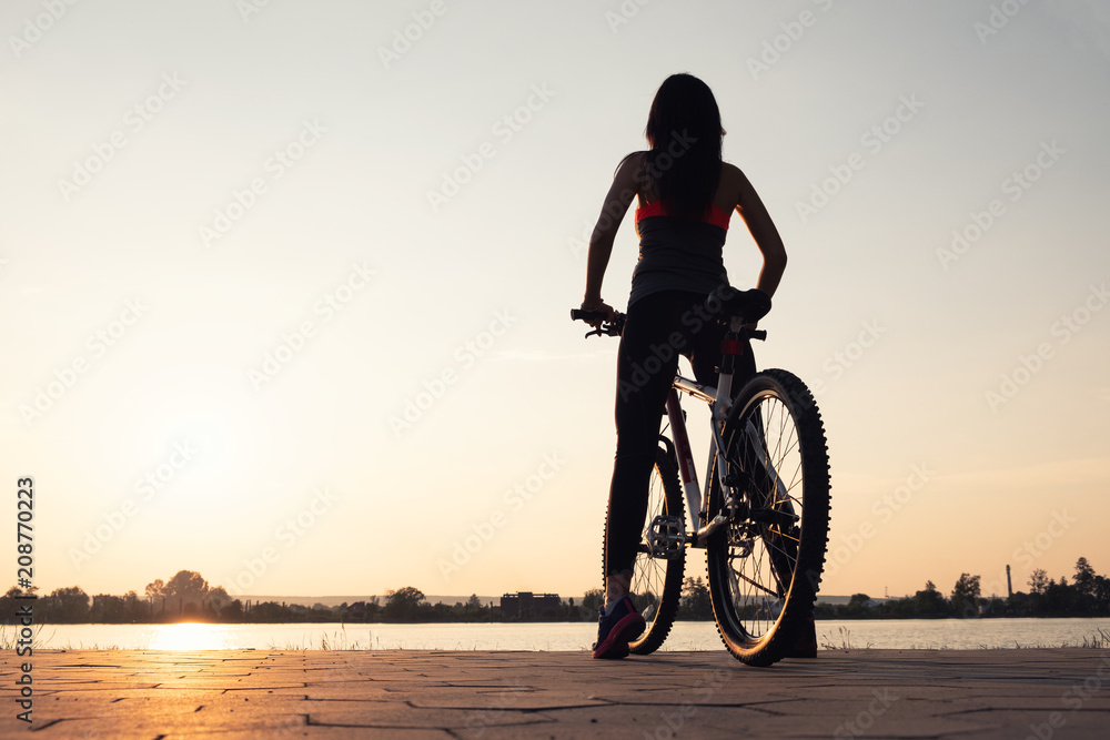 Fototapeta premium Silhouette of a girl near sea on the bike. Sport and active life concept