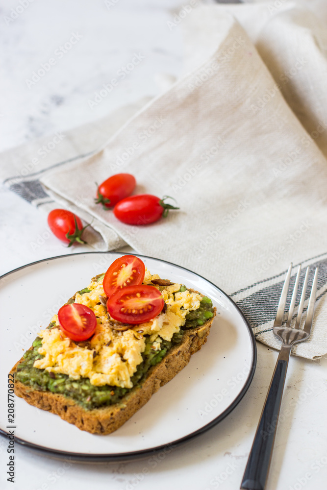 Scrambled eggs on whole wheat bread with avocado and cherry tomatoes Scrambled eggs on whole wheat bread with avocado and cherry tomatoes