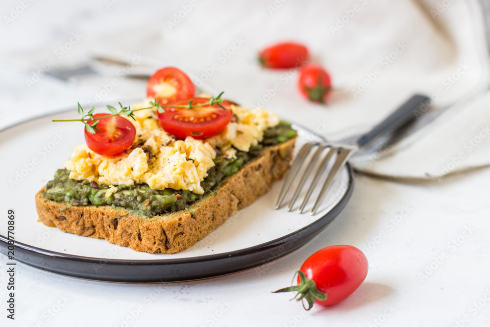 Scrambled eggs on whole wheat bread with avocado and cherry tomatoes Scrambled eggs on whole wheat bread with avocado and cherry tomatoes