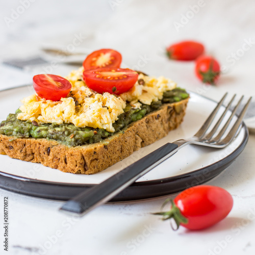 Scrambled eggs on whole wheat bread with avocado and cherry tomatoes