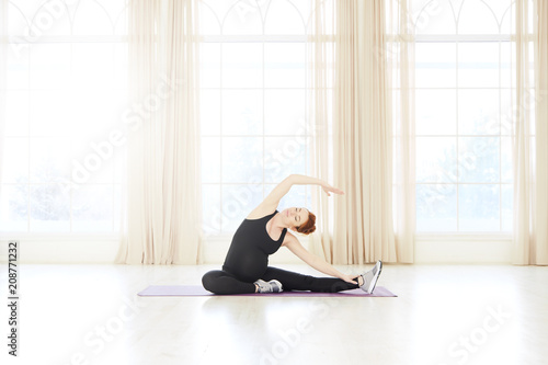  Young pregnant yoga woman working out near windows
