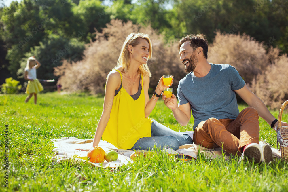 Cracking jokes. Alert loving wife smiling and her husband and their kids playing in the background