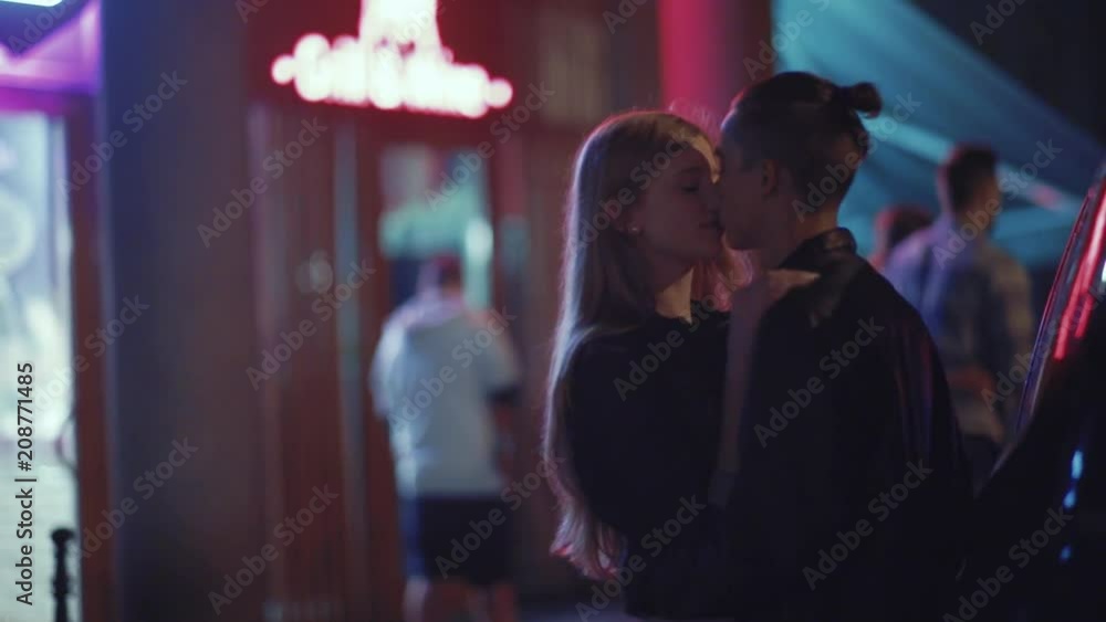 Romantic young couple standing by their car and passionately kissing. True feelings, having a date, enjoying each other. Love story, outdoors, night time Romantic young couple standing by their car and passionately kissing. True feelings, having a date, enjoying each other. Love story, outdoors, night time