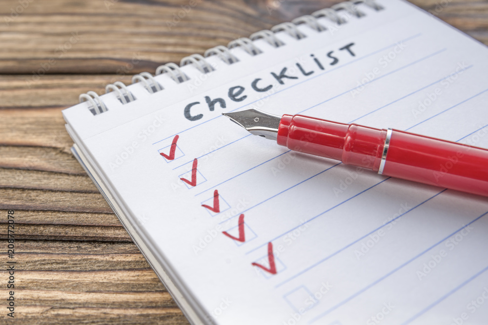 checklist, red pen on the background of a wooden table. close-up checklist, red pen on the background of a wooden table. close-up