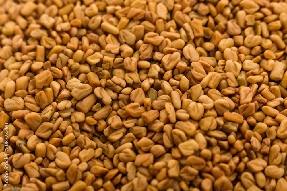 fragrant grains of fenugreek on a rustic background fragrant grains of fenugreek on a rustic background