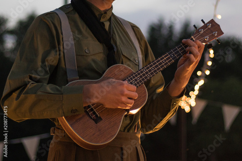 Man playing a ukulele outside on a summers evening