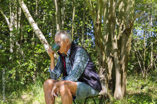 Man drinking from cup in forest photo