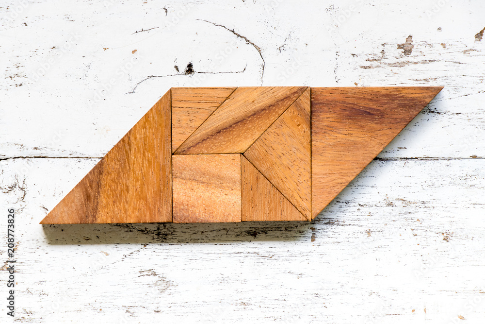 Tangram puzzle in parallelogram shape on old white wood background