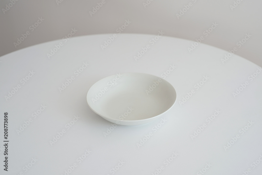 Fototapeta premium White plate stands on a white round table