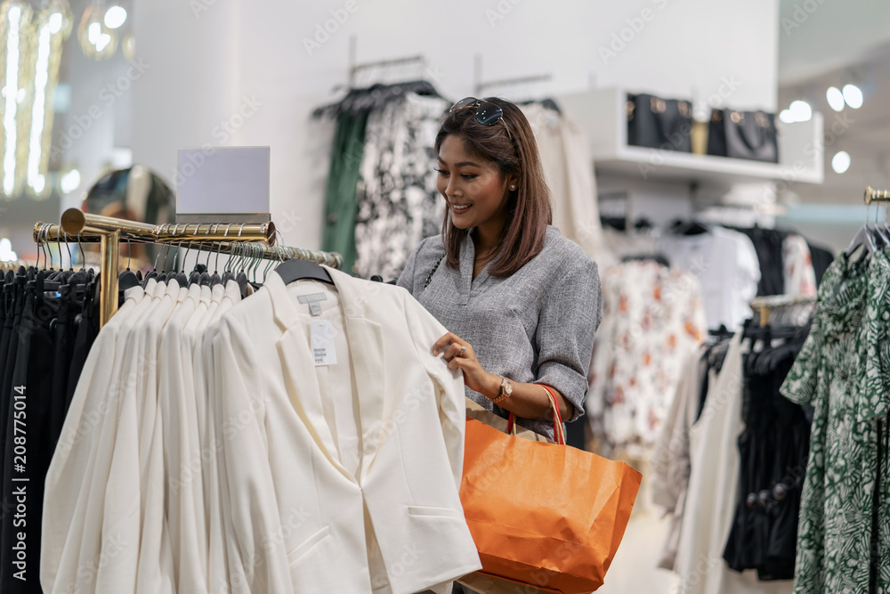 Happy Asian woman choosing clothes in shop store with happy action at department center Happy Asian woman choosing clothes in shop store with happy action at department center