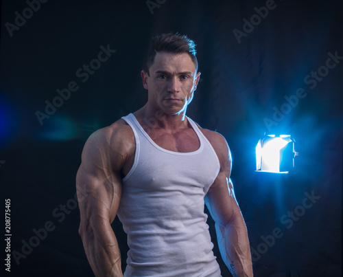 Handsome athletic muscle man in white t-shirt in studio on black, looking at camera