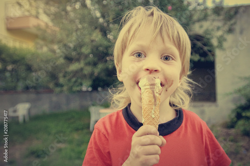 Принти на полотні Cute boy eating ice-cream during walk in tropical resort
