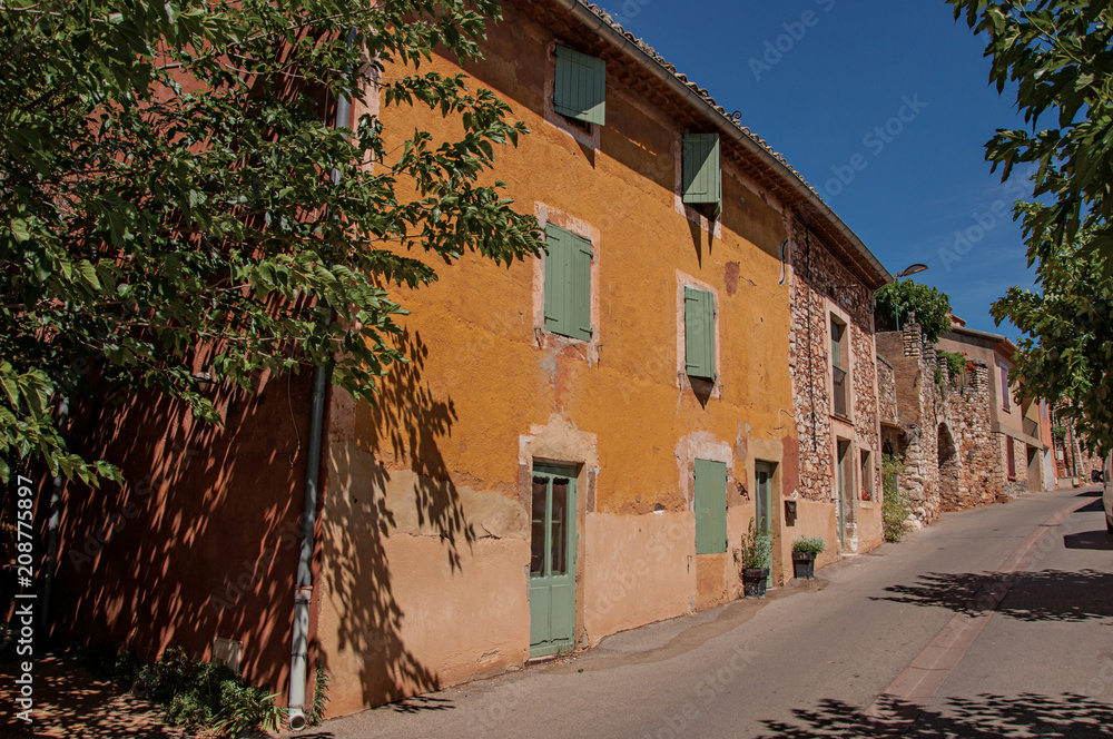 Fototapeta premium Traditional colorful houses in ocher and blue sky in the historic city center of Roussillon. In the Vaucluse department, Provence region, southeastern France.