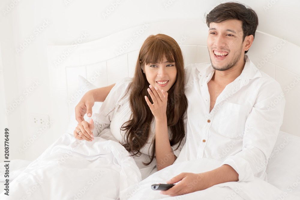 An attractive young couple lying in bed and watching movie. An attractive young couple lying in bed and watching movie.