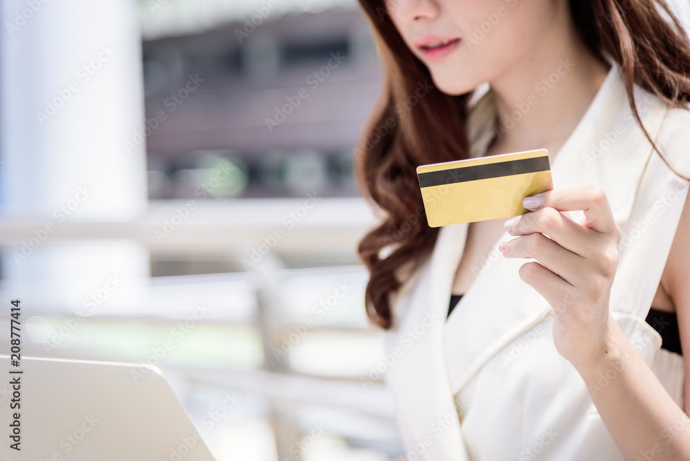 The asian business woman has shopping and buying with credit card from outside office with building and city background. The asian business woman has shopping and buying with credit card from outside office with building and city background.