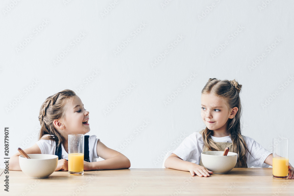 adorable smiling schoolgirls eating cereals with orange juice for breakfast isolated on white adorable smiling schoolgirls eating cereals with orange juice for breakfast isolated on white