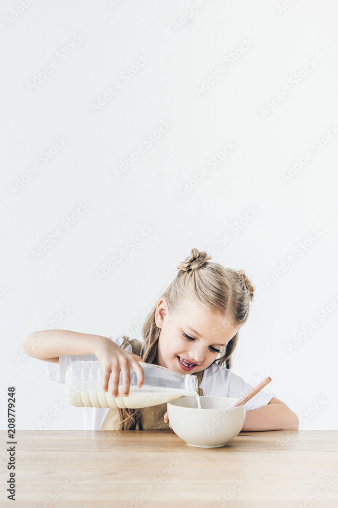 smiling little schoolgirl pouring milk into cereal for breakfast isolated on white smiling little schoolgirl pouring milk into cereal for breakfast isolated on white