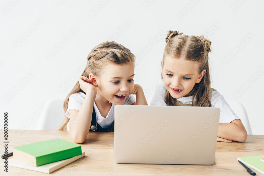 excited little schoolgirls using laptop for studying isolated on white