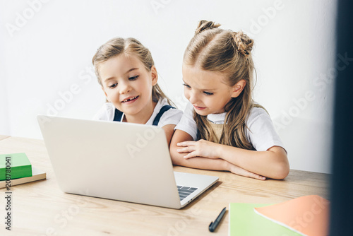 happy little schoolgirls using laptop for studying isolated on white