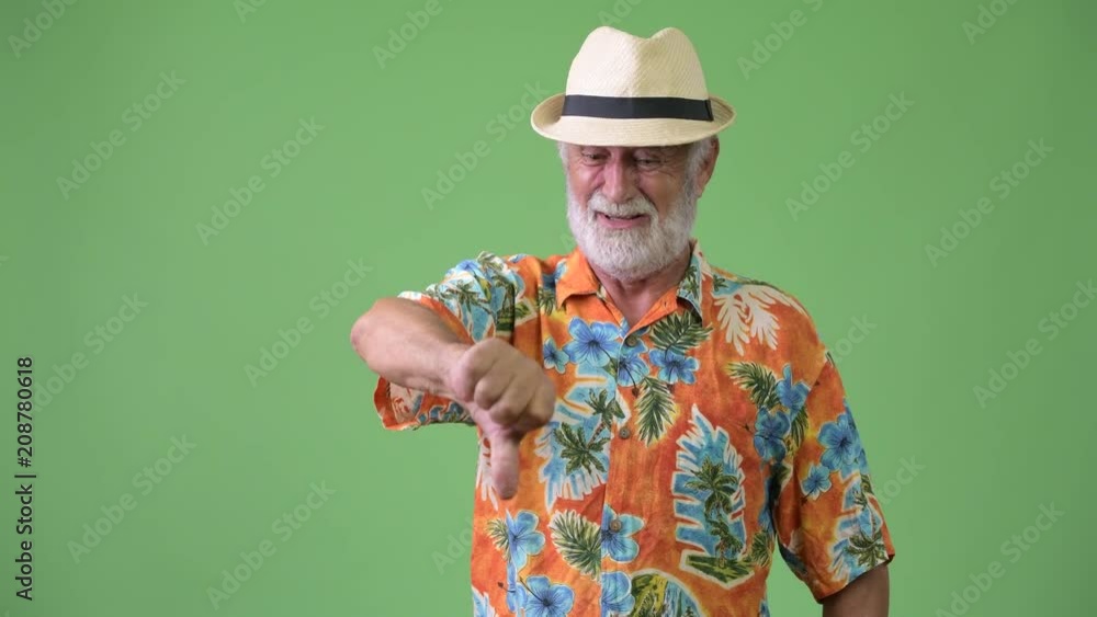 Handsome senior bearded tourist man ready for vacation against green background Handsome senior bearded tourist man ready for vacation against green background