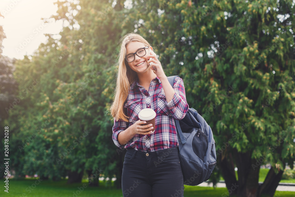 Obraz premium Student girl talking on mobile with coffee cup
