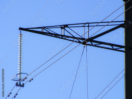 High voltage current line structure in close up. View of electrical distribution fuses. Power supply metal construction with blue sky background. © Uldis