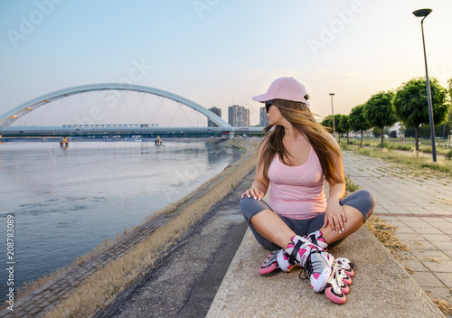 Roller girl resting after drive, sitting on concrete wall