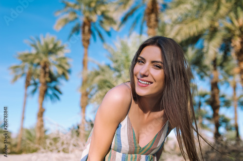 Holidays woman smiling at camera on tropical beach summer vacation with palm trees and date palms