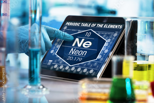 scientist consulting on the digital tablet data of the chemical element Neon Ne / researcher working on the computer with the periodic table of elements