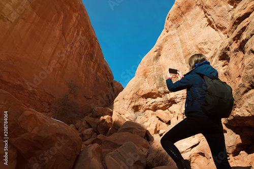 Female photographer takes picture with rock formation in the Arches National Park, Utah, USA