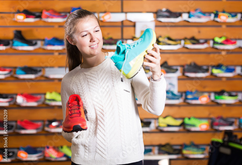 Portrait of young cute woman choosing sport shoes