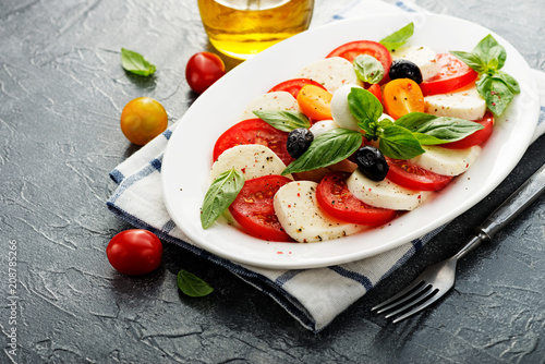 Delicious caprese salad with  tomatoes,mozzarella cheese and fresh basil leaves. Italian food. top view