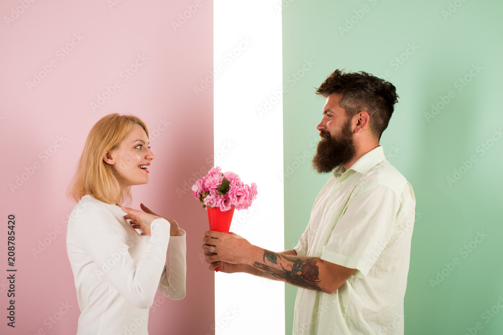 Man with beard congratulates woman birthday anniversary holiday. Hipster bearded give bouquet flowers to girlfriend. Couple date bouquet flowers gift. Gift concept. Couple in love celebrating holiday Man with beard congratulates woman birthday anniversary holiday. Hipster bearded give bouquet flowers to girlfriend. Couple date bouquet flowers gift. Gift concept. Couple in love celebrating holiday