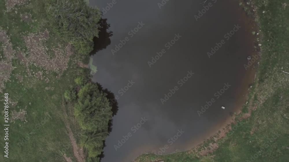 Aerial view. Top view flying up above a mountain lake surrounded by green pine trees Aerial view. Top view flying up above a mountain lake surrounded by green pine trees