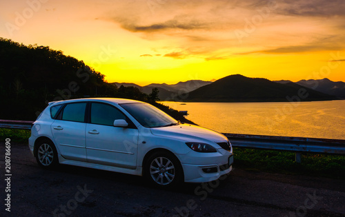 Fototapeta Naklejka Na Ścianę i Meble -  White sport car parking at dam in sunset and sunrise