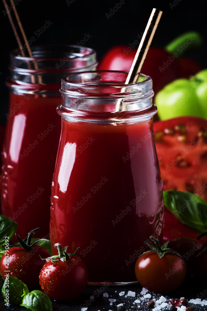 Spicy tomato juice with chili, bell peppers and green basil in glass bottles on black background, selective focus Spicy tomato juice with chili, bell peppers and green basil in glass bottles on black background, selective focus