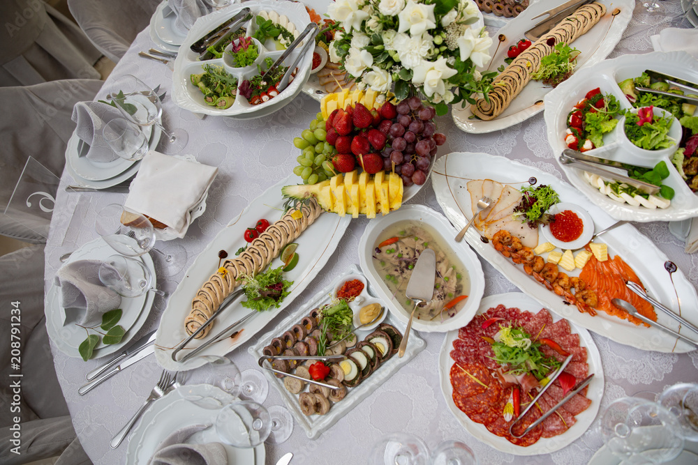 Buffet table of reception with cold snacks, meat, salads and fruits