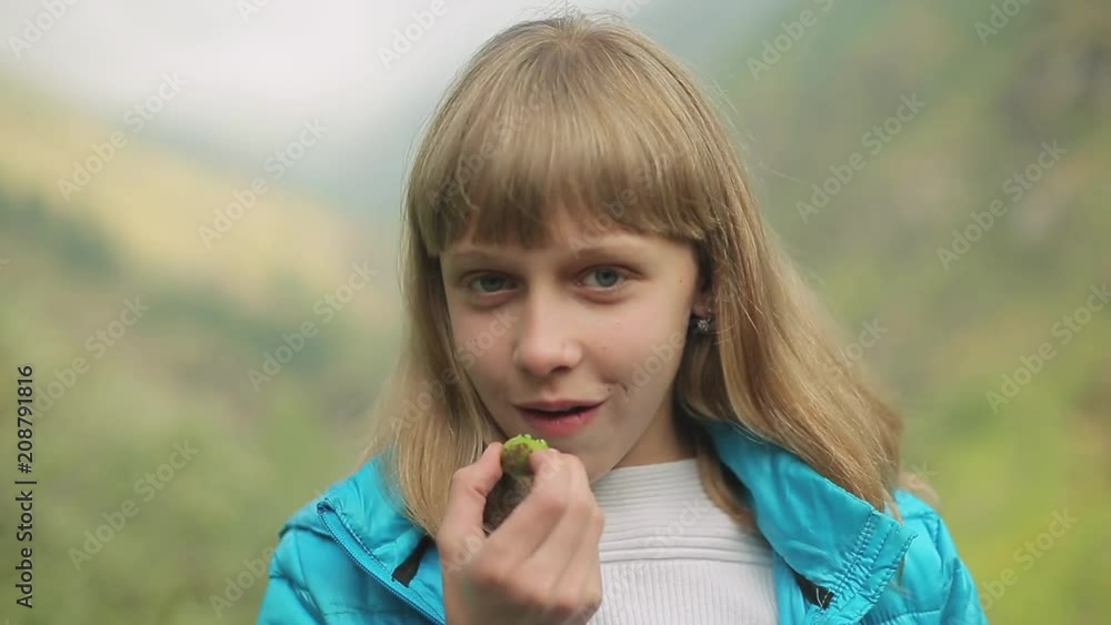 Portrait of a young beautiful woman, in the mountains in summer, eating sour green apricot Portrait of a young beautiful woman, in the mountains in summer, eating sour green apricot