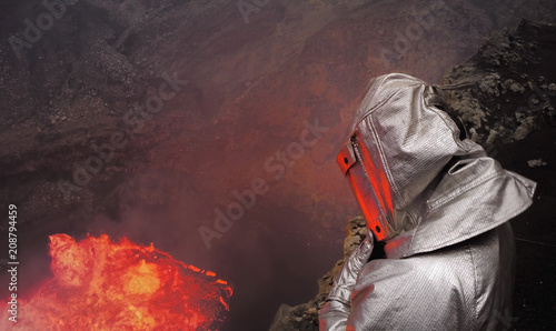 A volcanologist stands in dangerous proximity to a crater with molten lava in a thermo-suit photo
