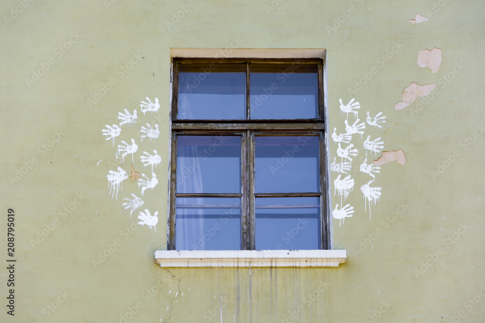 the window of the building with peeling paint on the walls and prints of child handprints on the wall outside to the left and right of the window the window of the building with peeling paint on the walls and prints of child handprints on the wall outside to the left and right of the window