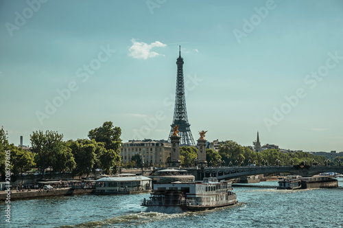 Boat on the Seine River, bridge and Eiffel Tower at sunset in Paris. Known as the “City of Light”, is one of the most awesome world’s cultural center. Northern France.