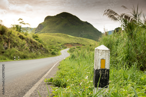 black and white milestone on asphalt roadside with laos landscape
